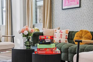 Una sala de estar con un sofá verde, una mesa de centro negra y un florero con flores.