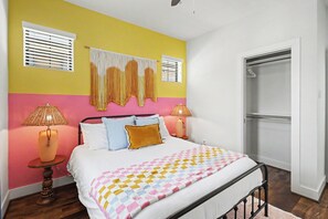Un dormitorio con cama, dos lámparas de noche, un adorno de macramé en la pared y un armario con puerta corredera.