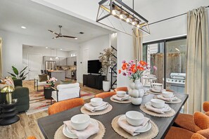 Un salon moderne comprenant un coin repas, une cuisine et un balcon avec un barbecue.