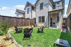 Un jardin avec un foyer, deux fauteuils Adirondack et une table de patio.