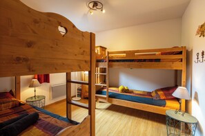 A cozy room with a bunk bed, a small table with a lamp, and a ladder leading to the upper bunk. - Chalet La Rua, 70 m² - 15 minutes from the slopes - L'Ostal Conciergerie (Risoul)