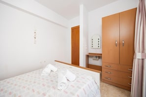 Una camera da letto con un letto, un armadio, uno specchio e un punto luce a parete.