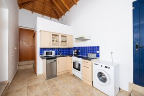 A compact kitchen with a microwave, toaster, coffee maker, oven, and washing machine.