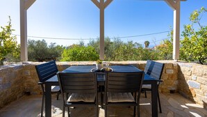 An outdoor patio with a table and chairs, stone walls, and a view of the landscape. - Panorama II Villas - Two Bedroom Villa, Sleeps 7 (Ditiki Mani)
