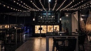 A bar area with string lights, a bar counter, and a seating area with chairs. - Hotel Three Seasons (Panigaon)
