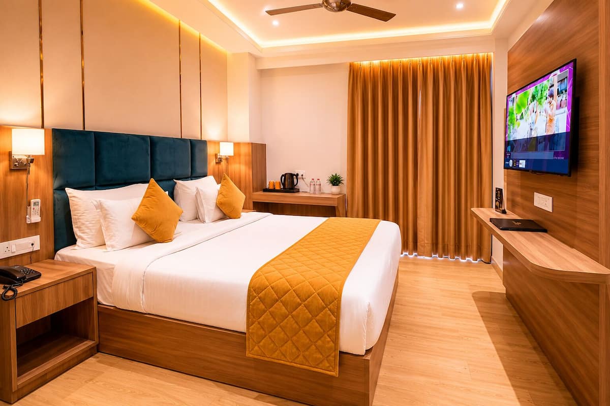 Una moderna camera d'albergo con un letto, comodini, una TV e una scrivania.