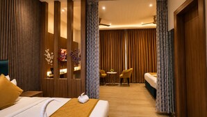 A hotel room with a bed, a desk, two chairs, a small table, and a curtain divider. - Hotel Three Seasons (Panigaon)