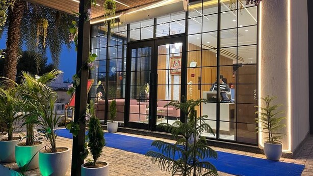 A modern building with large glass windows, a blue carpeted entrance, and potted plants. - Hotel Three Seasons (Panigaon)