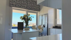 A modern kitchen with a large window, a vase of flowers, and a refrigerator. - 21 Cheviot Place (Cape Town)