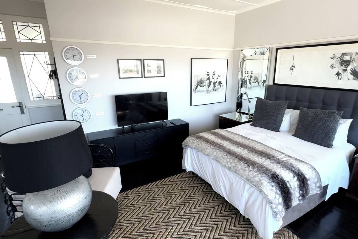 A modern bedroom with a large bed, a TV, a desk, and a chair.