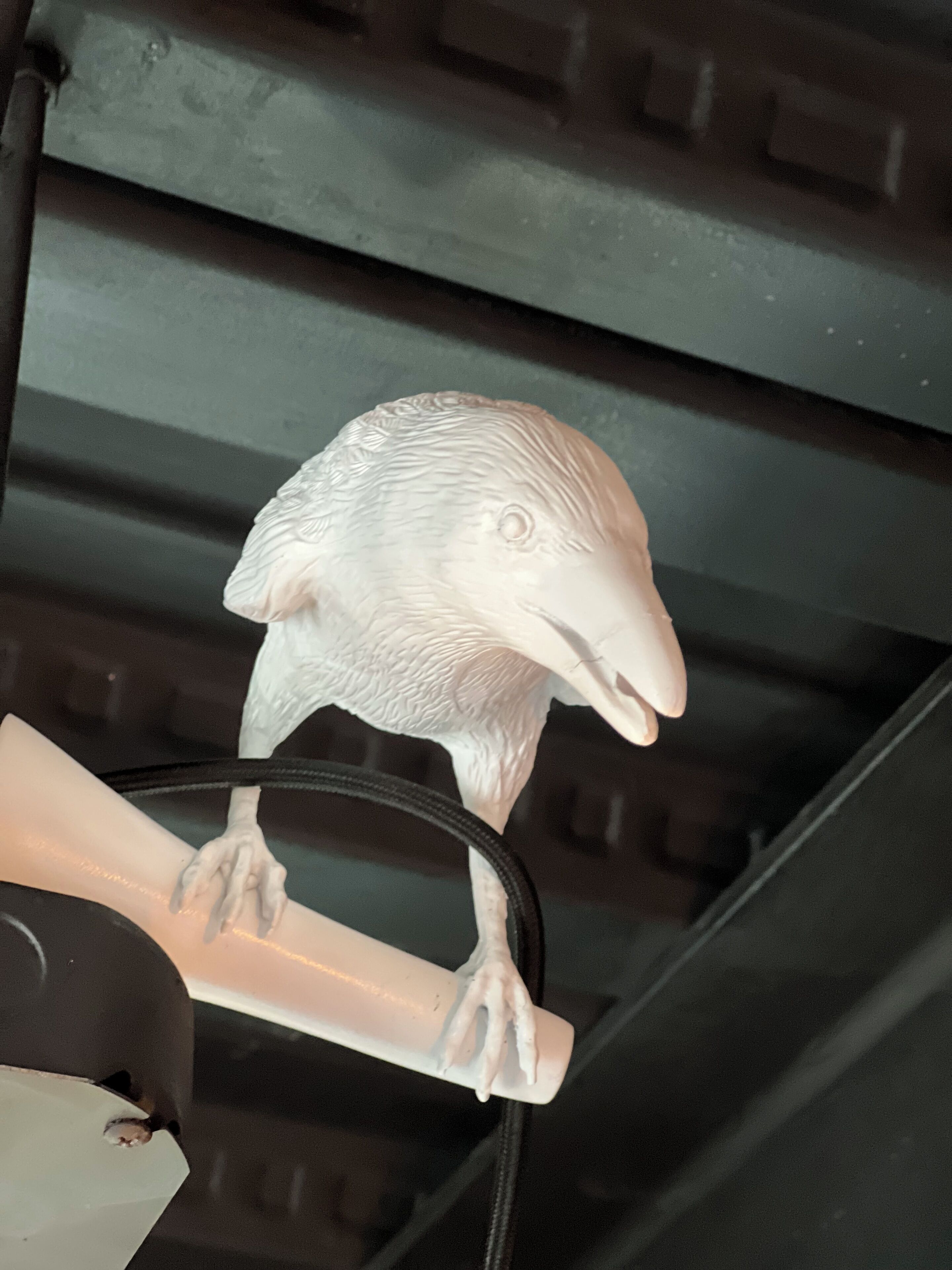 A bird figurine on a white stand.