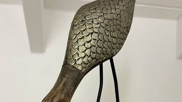 A decorative bird sculpture with a textured metallic body and a wooden base.