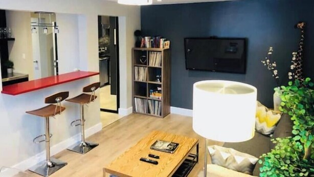 Una sala de estar moderna con una mesa de centro de madera, una encimera roja y una estantería.