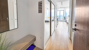 A hallway with a bench, a family sign, and a view into a room with a bed and a balcony.