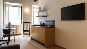 A compact kitchen with a sink, kettle, and a small countertop. There is a chair and a table in the adjacent dining area. - Vacation home in Tivoli - Residenza San Valerio in the historic center (Tivoli)