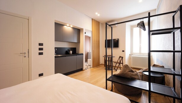 A modern bedroom with a large bed, a kitchenette, a dining area with a table and chairs, and a TV mounted on the wall. - Vacation home in Tivoli - Residenza San Valerio in the historic center (Tivoli)