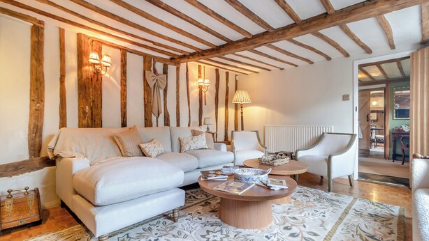 A cozy living room with a sectional sofa, a round coffee table, and a patterned rug. - 3 bedroom accommodation in Saffron Walden (Saffron Walden)