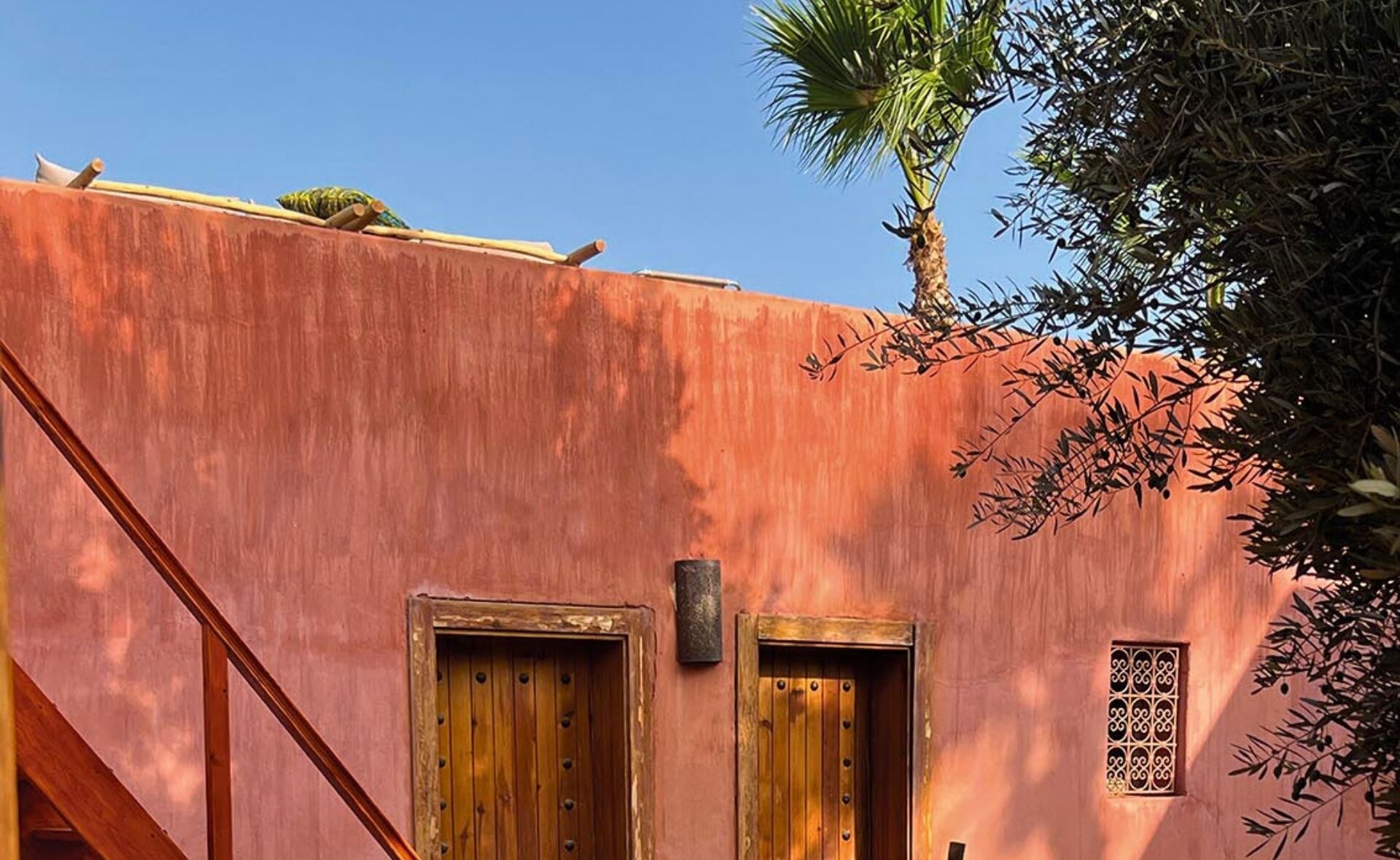 Un edifici amb façana rosa, dues portes de fusta i una petita finestra decorativa.