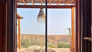 Une porte ouverte donnant sur un patio d’où l’on peut admirer un paysage désertique.