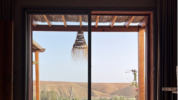 Une pièce dotée d’une grande porte-fenêtre coulissante qui donne sur un patio extérieur offrant une vue sur un paysage désertique.