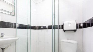 A modern bathroom with a glass shower enclosure, a white sink, and a toilet.