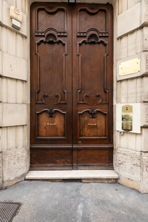A large, ornate wooden door with a brass handle and a plaque above it. - Elegant Salandra Suite (Rome)