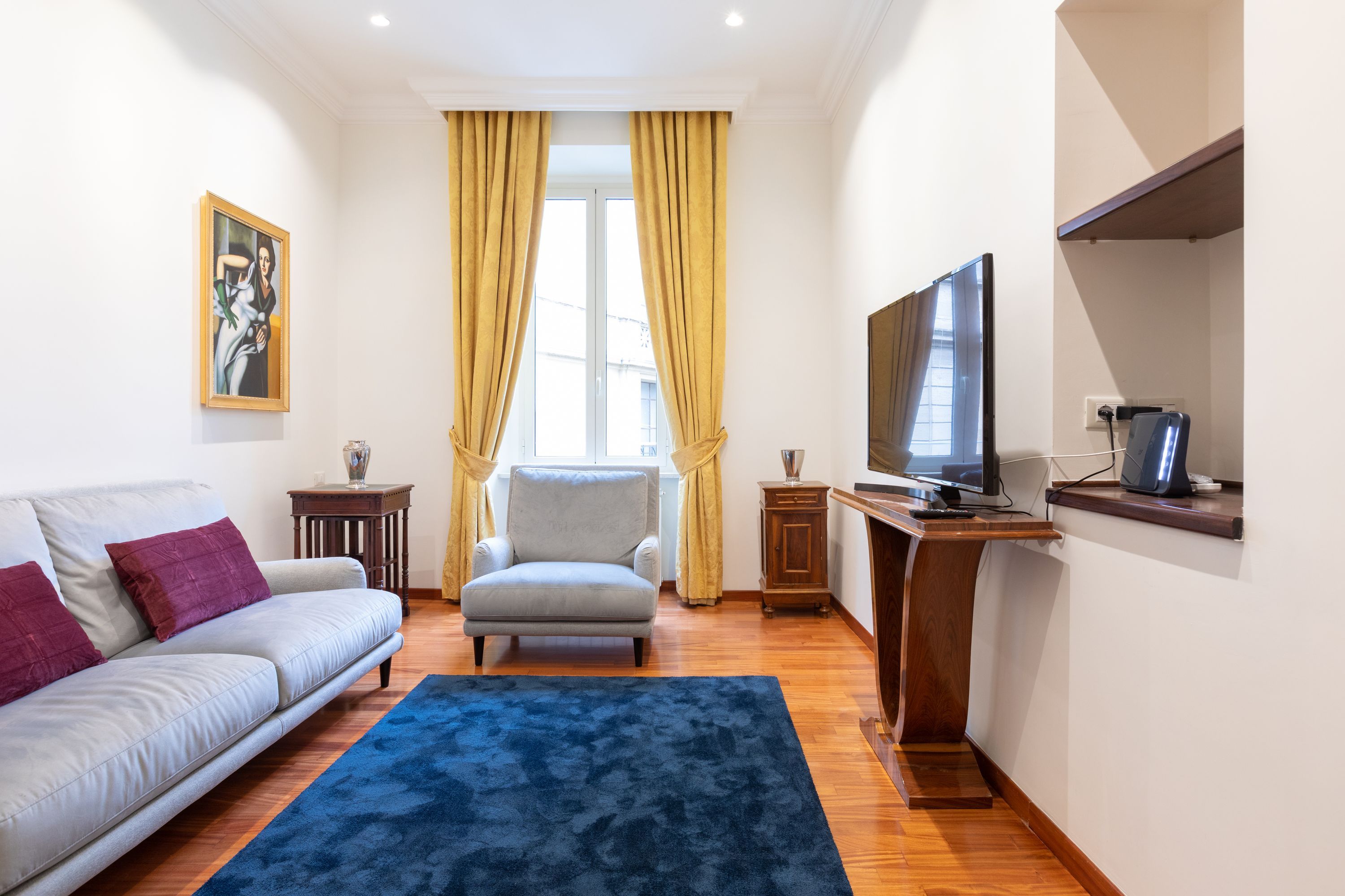 Una sala de estar con sofá, sillón, televisor y aparador de madera.