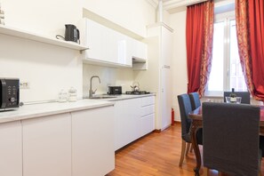 A modern kitchen with white cabinets, a microwave, a kettle, and a coffee maker. - Elegant Salandra Suite (Rome)