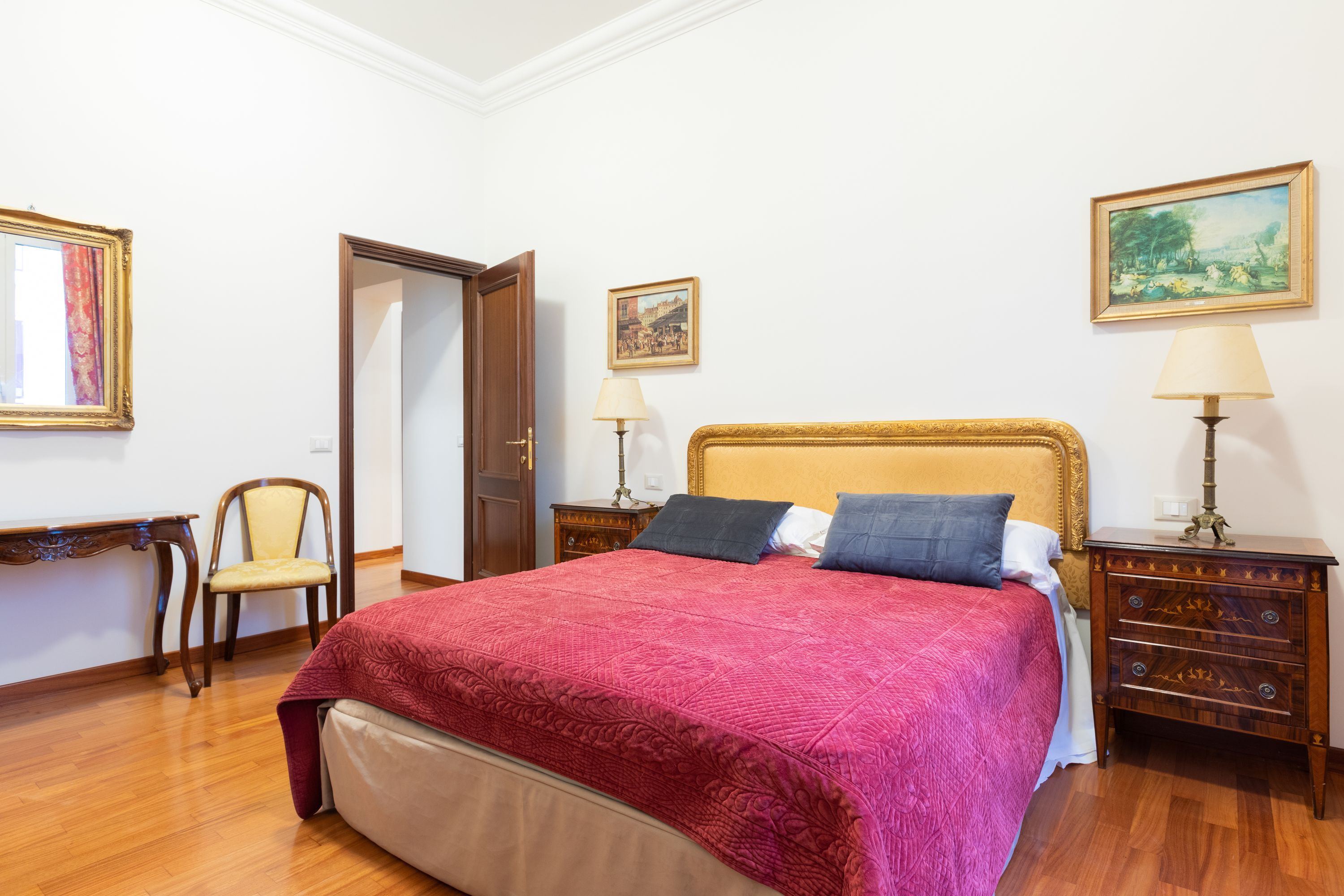 A hotel room with a large bed, wooden nightstands, a chair, and a desk.