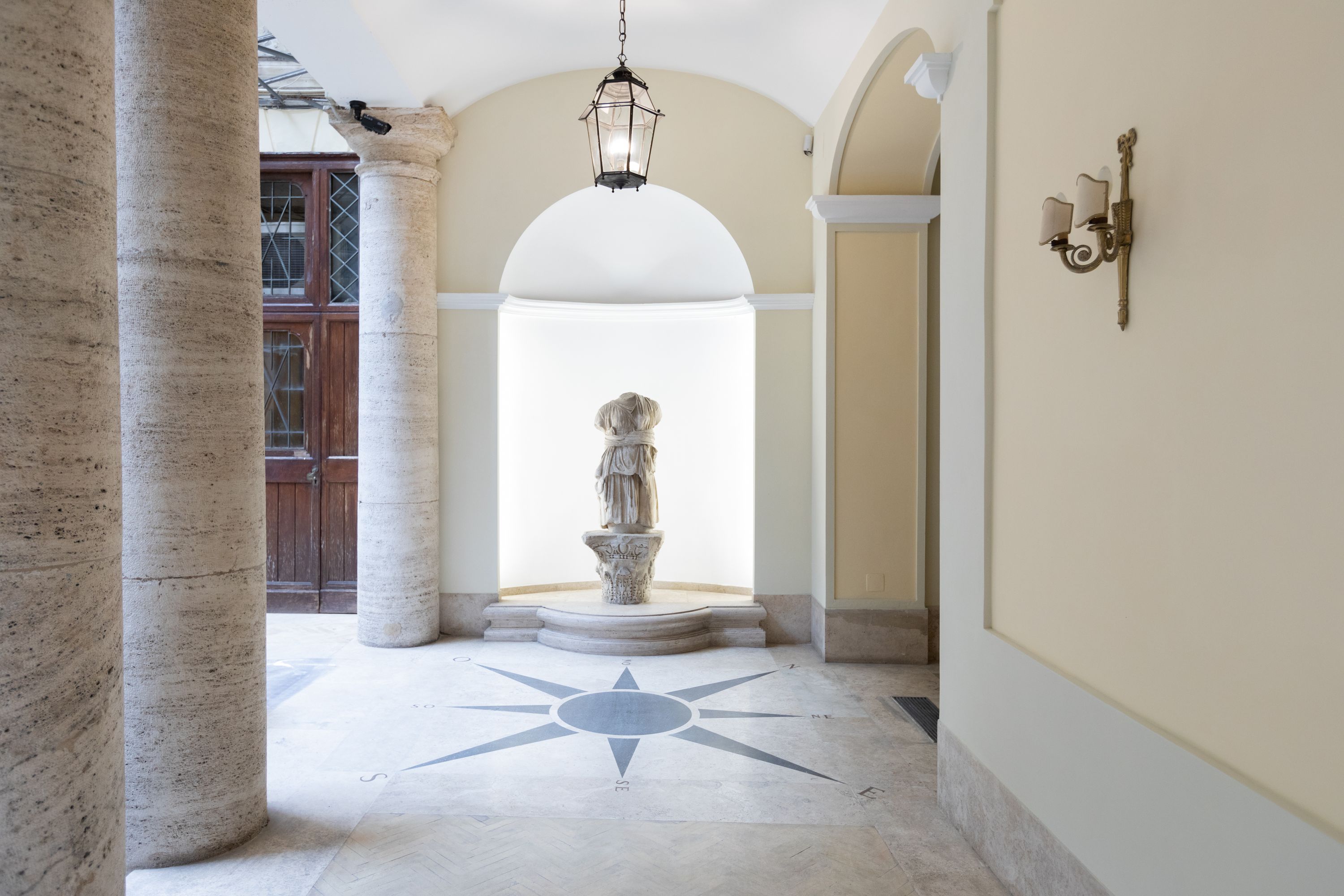 A hallway with a central statue, columns, and a star-patterned floor.