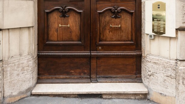 A large, ornate wooden door with a brass handle and a plaque above it. - Elegant Salandra Suite (Rome)