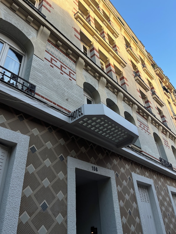 A hotel facade with a prominent "HOTEL" sign, a numbered entrance, and a patterned exterior. - La Lumière de Paris (Levallois-Perret)