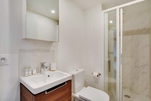 A modern bathroom with a white sink, mirror, and toilet. - La Lumière de Paris (Levallois-Perret)