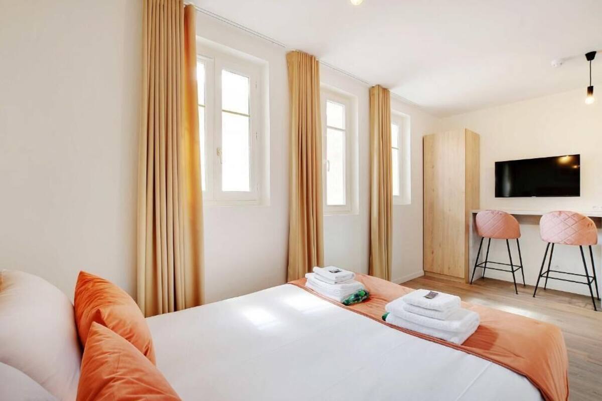 Una camera d'albergo con un letto, una scrivania, due sedie, una televisione e tende.