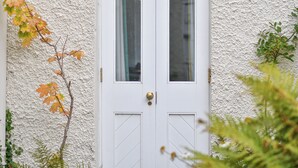 A white door with a brass handle and glass panels, set against a textured wall. - Edwardian Beach Villa in Whitehead, Beach Front Period Edwardian Villa (Whitehead)