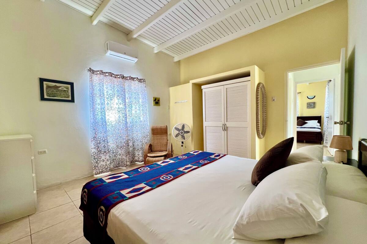 Une chambre à coucher avec un lit, une chaise, un ventilateur et une armoire.