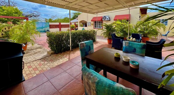An outdoor patio with a table and chairs, surrounded by potted plants and a tiled floor. - Bubali Gardens by Kamerlingh Villa (Noord)