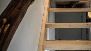 Een houten trap met een natuurlijke houten leuning en een witte muur.