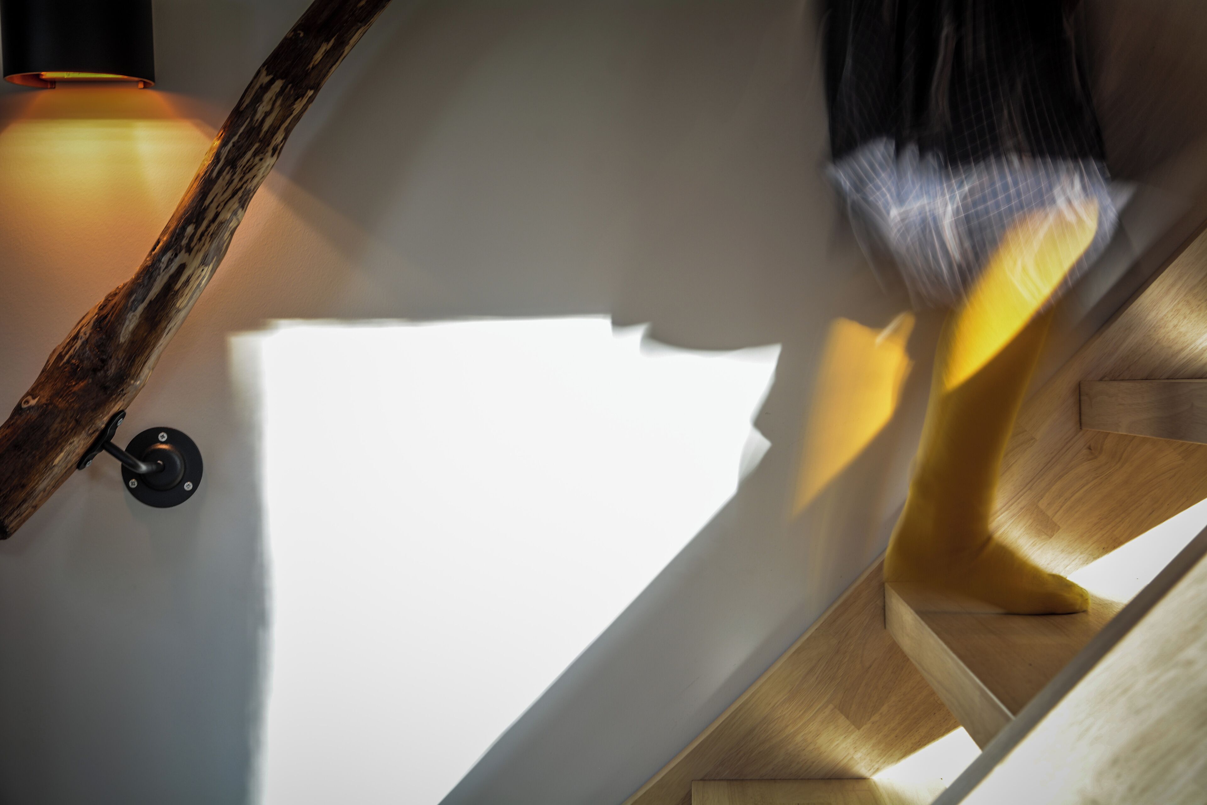 A staircase with a wooden handrail and a wall-mounted light fixture.