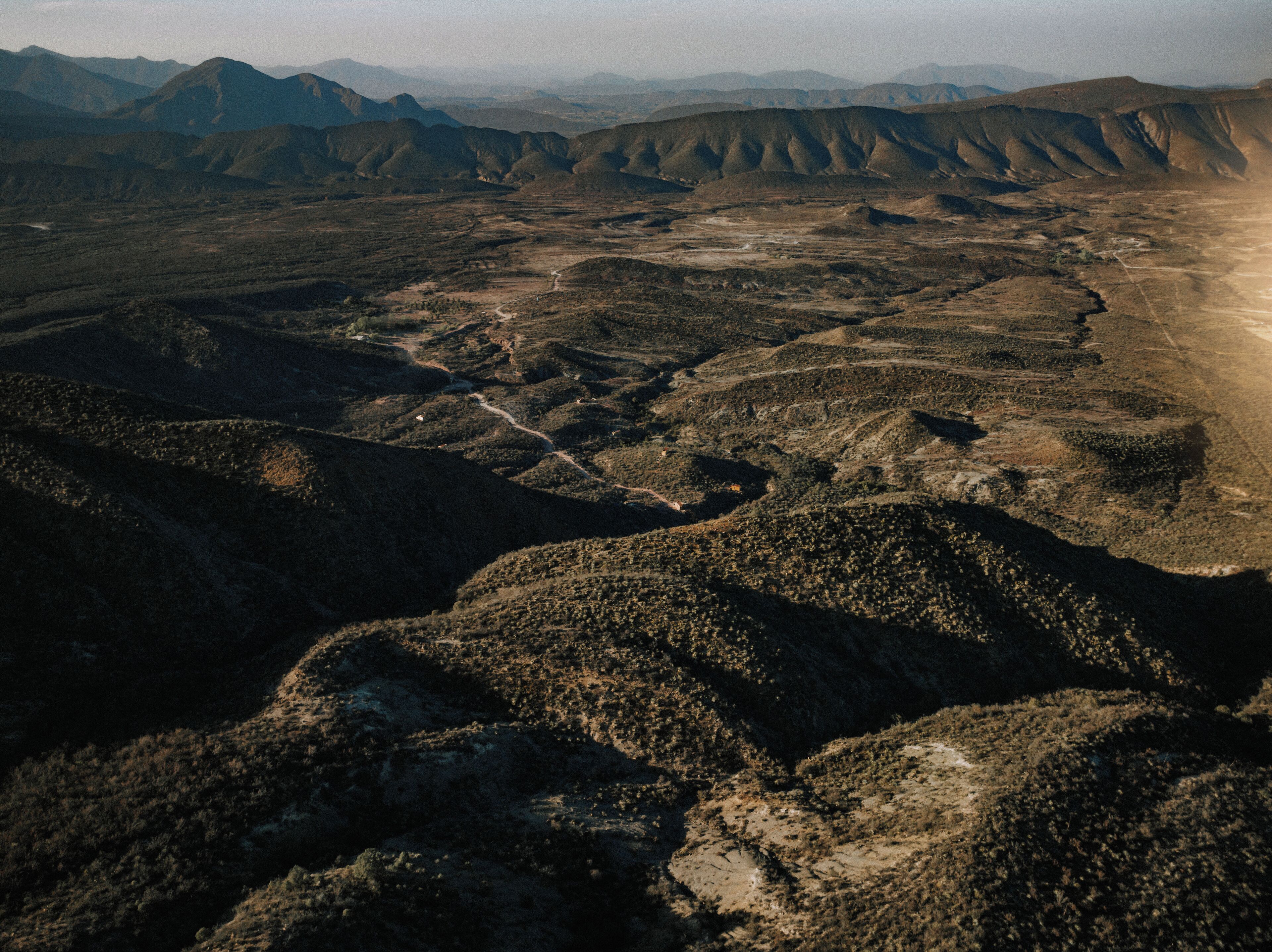 A panoramic view of a rugged landscape with undulating terrain and distant mountains.