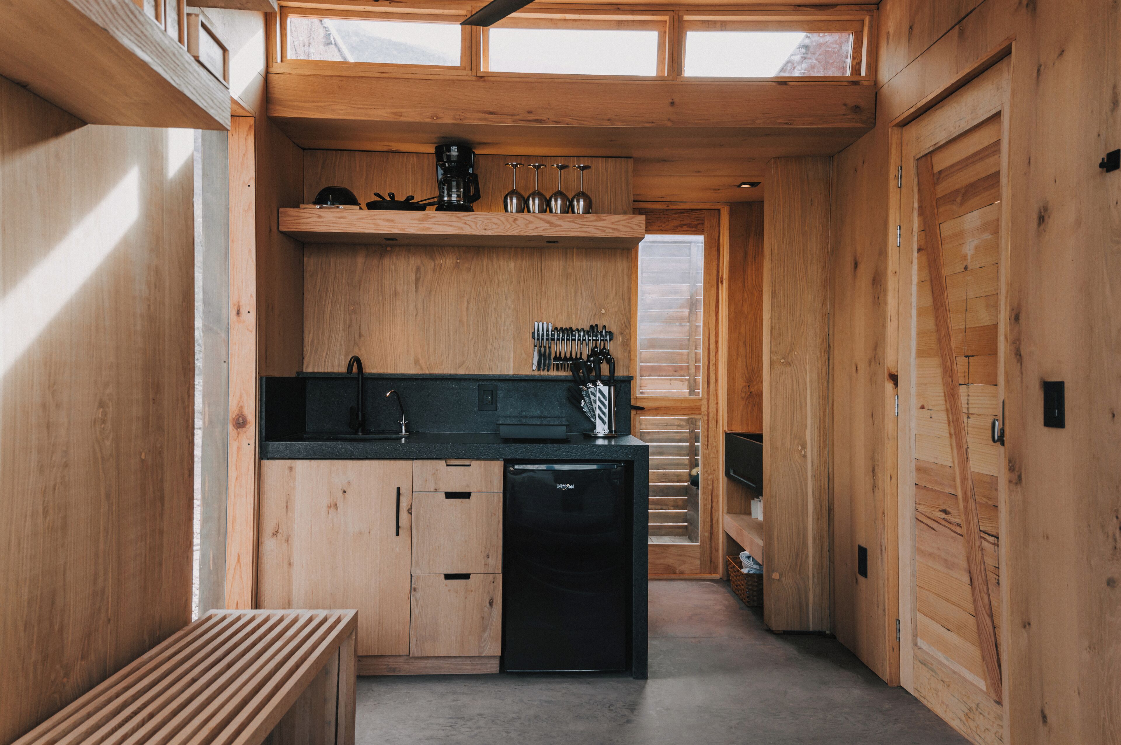 A compact kitchen with wooden cabinetry, a black dishwasher, and a coffee maker.