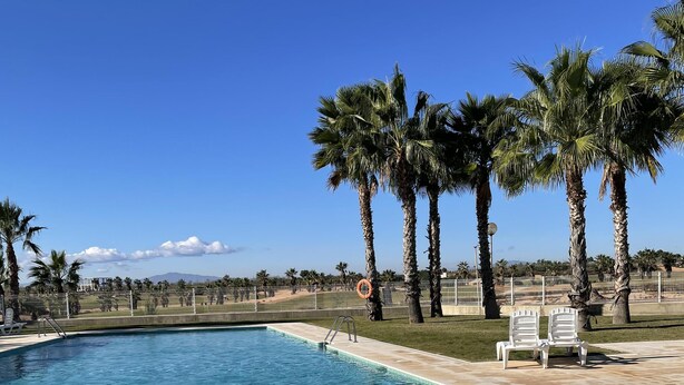 A clear blue pool with a tiled edge, surrounded by palm trees and a fenced area. - Hancinda Sleeps 4 With Free Parking (Fuente Alamo de Murcia)