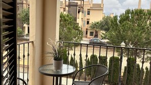 A balcony with a round table and two chairs, overlooking a courtyard with trees and buildings. - Hancinda Sleeps 4 With Free Parking (Fuente Alamo de Murcia)