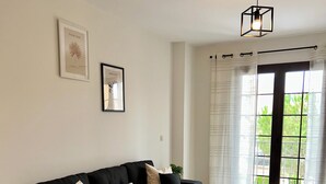 A modern living room with a black sofa, a round coffee table, and a large window with curtains. - Hancinda Sleeps 4 With Free Parking (Fuente Alamo de Murcia)