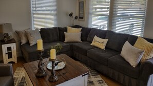 A living room with a sectional sofa, a coffee table with candles, and a side table with a lamp.