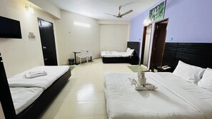 A hotel room with two beds, a desk, a chair, a TV, and a ceiling fan. -  Hotel Royal Palm (Sylhet)