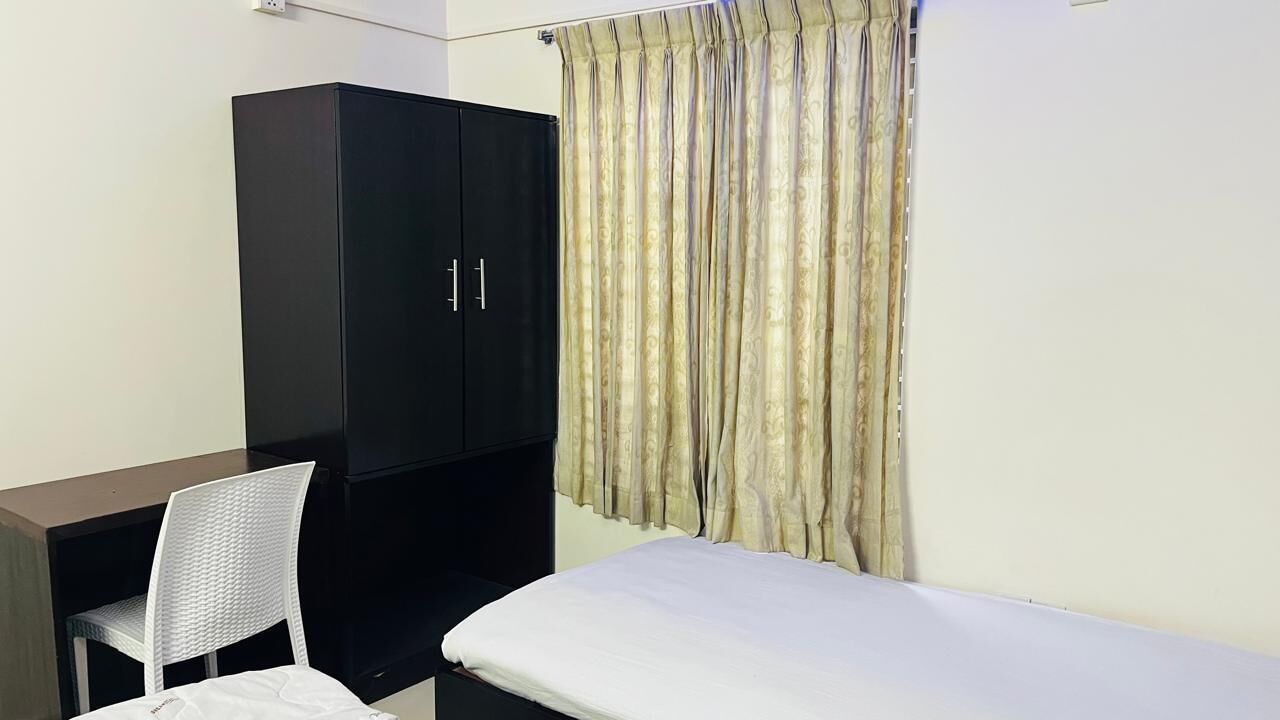 A bedroom with a bed, a wardrobe, and a chair.