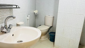 Une salle de bain équipée d’un lavabo, de toilettes et d’une poubelle.