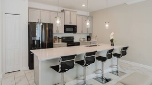 A modern kitchen with a large island, stainless steel appliances, and bar stools.