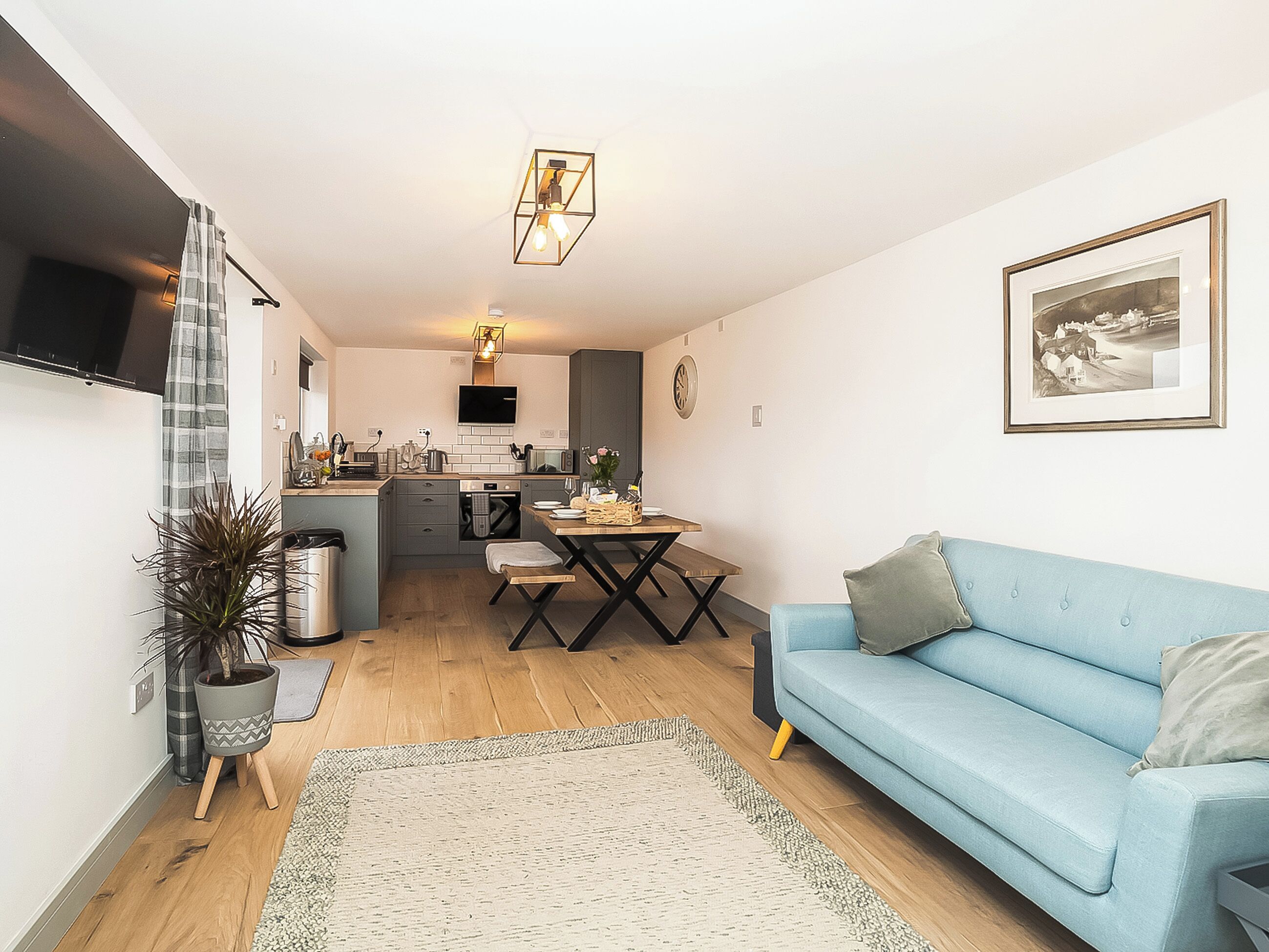 A compact living space with a kitchenette, dining area, and a light blue sofa.